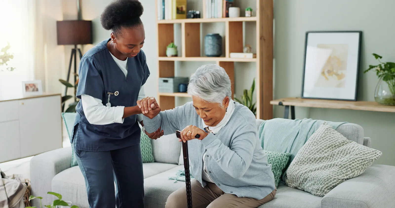 Nurse helping an older woman steady herself as she stands