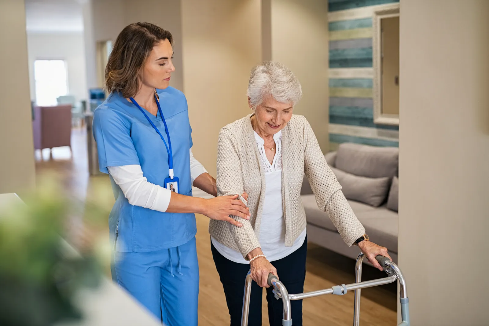 Care assistant helping a woman walk with her frame
